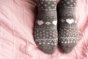 Feet in warm socks on the bedspread