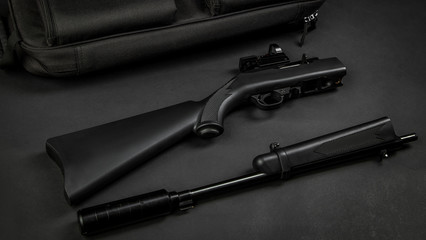 disassembled black rifle 22lr with a collimator sight and a silencer on a black