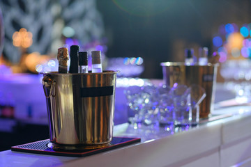 Bottle of champagne in bucket of ice. Bar counter.