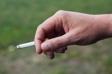 closeup of man with cigarette in hand in outdoor