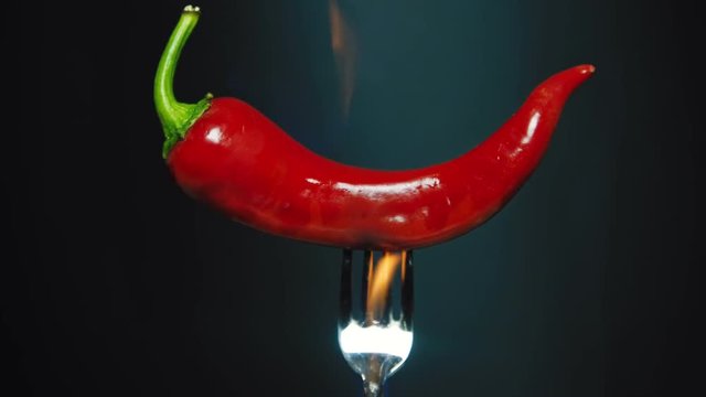 Red hot chili pepper with flame at the black background. 4K