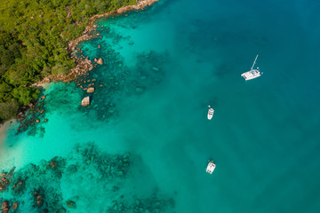 Spectacular aerial view of some yachts and small boats floating on a clear and turquoise sea, Seychelles in the Indian Ocean.Top view from drone