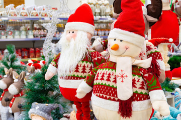 Christmas soft toy, snowman and Santa Claus. Santa Claus with a friend in the shop windshield.