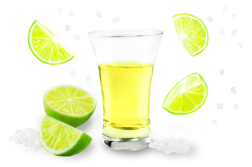 Glass of tequila liquor with falling salt and lime fruits isolated