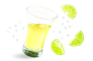Glass of tequila liquor with falling salt and lime fruits isolated