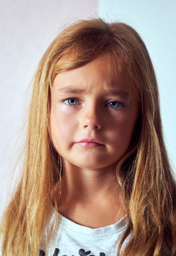 Portrait of adorable llitle six or seven years old girl feels unhappy posing looking at camera