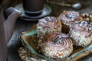biscuit cake sprinkled with nut crumb and decorated with chocolate cream are next to teapot and cup