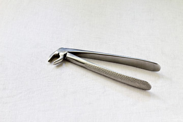 Medicine. Retro. Dental steel forceps for removal of teeth on white gauze background. Black and white photo.