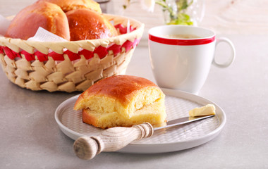 Bun sliced a knife with butter near on plate