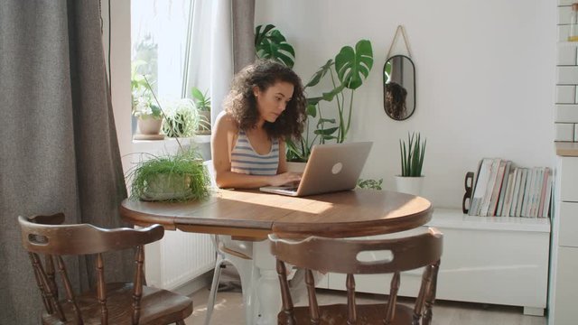 Charming young woman typing on laptop computer at home.