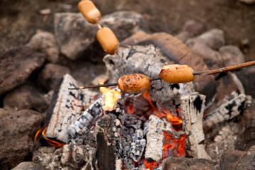 Cook sausages on the fire.