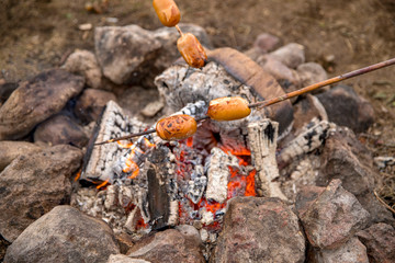 Cook sausages on the fire.