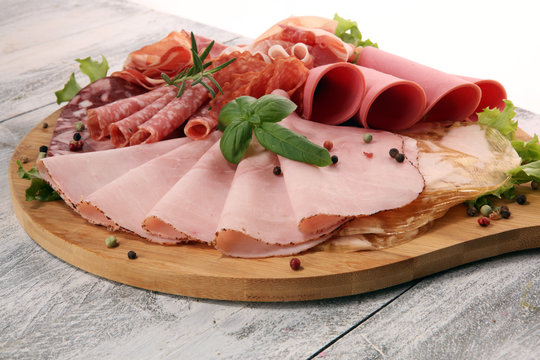 Food tray with delicious salami, pieces of sliced ham, sausage and salad. Meat platter with selection.