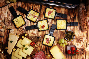 Delicious traditional Swiss melted raclette cheese served in individual skillets with salami.