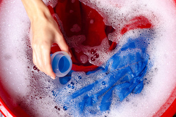 Women washing color clothes in basin enemale powdered detergent liquid laundry gel, top view