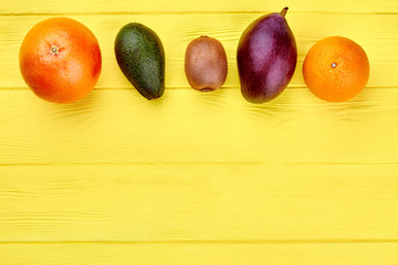 Row of colorful fruits and copy space. Assortment of fresh organic fruits on light wooden background. Ingredietns for fruity salad.