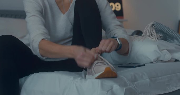 Attractive sporty young Caucasian woman getting ready for exercising early in the morning, tying her sports shoe. 4K UHD