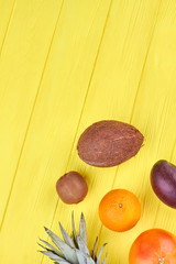 Tasty exotic fruits and copy space. Top view on mixed tropical fruits on yellow wooden surface with text space on top.