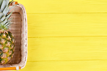 Whole green pineapple in basket and copy space. Tropical ananas fruit in wicker basket and text space.