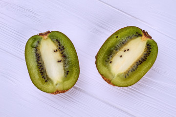 Two halves of kiwifruit on light wooden surface. Ripe juicy kiwi fruit sliced on two parts on...