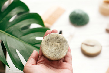 Zero waste. Choice plastic free eco products. Hand holding natural solid shampoo bar on background...
