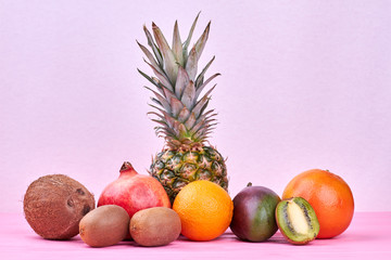 Composition from tropical fruits on pink background. Assortment of exotic fruits and copy space.