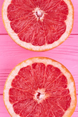 Sliced halves of fresh grapefruit. Ripe delicious grapefruit cutted on two pieces on pink wood close up.