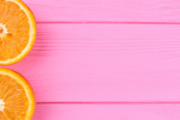 Two halves of oranges and copy space. Fresh juicy oranges on pink wooden background and text space....