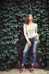 Portrait of a latin woman posing near a wall with a green grapes leaves.