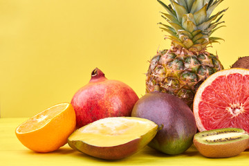 Assortment of fresh tropical fruits. Mix of ripe exotic fruits on yellow background. Summer fruits refreshment.