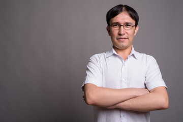 Young Asian nerd man wearing eyeglasses against gray background
