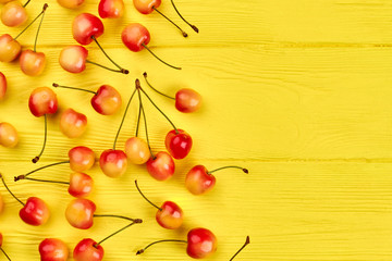 Obraz na płótnie Canvas Ripe sweet cherries and copy space. Delicious cherries on yellow wooden background and text space. Healthy nutritious berries.