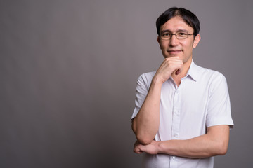 Young Asian nerd man wearing eyeglasses against gray background