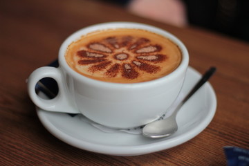 Top view of Latte hot coffee (or cappuccino) in a green cup with latte art and roasted coffee beans on wooden table background