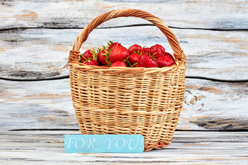 Fototapeta na wymiar Healthy summer strawberries in basket. Ripe delicious strawberries in basket on vintage wooden surface. Beautiful fruity gift.