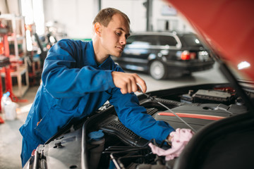 Male technician works with car engine