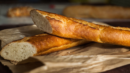 Fresh baguetteon paper bag, on wooden table, close up