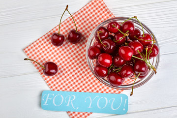 Ripe fresh cherries on wooden background. Healthy summer berries in bowl and paper card with text for you. Love and romance.