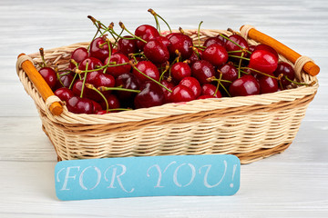 Fresh delicious cherries in basket. Ripe sweet berries on white wooden background. Romantic fruity concept.