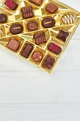 Assortment of chocolate candies, top view. Various tasty candies in golden box and copy space. Sweet gift on Valentines Day.