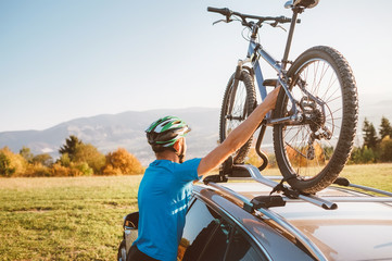 Mountain biker man take of his bike from the car roof