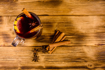 Cup of mulled wine with cinnamon on wooden table. Top view