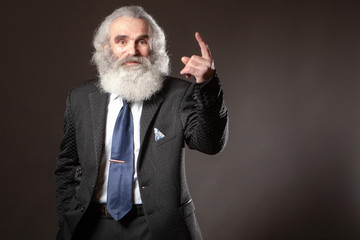 Grandpa with a big beard. An elderly man shows his finger to the top. Gray beard. Beliefs. Gray-haired man.