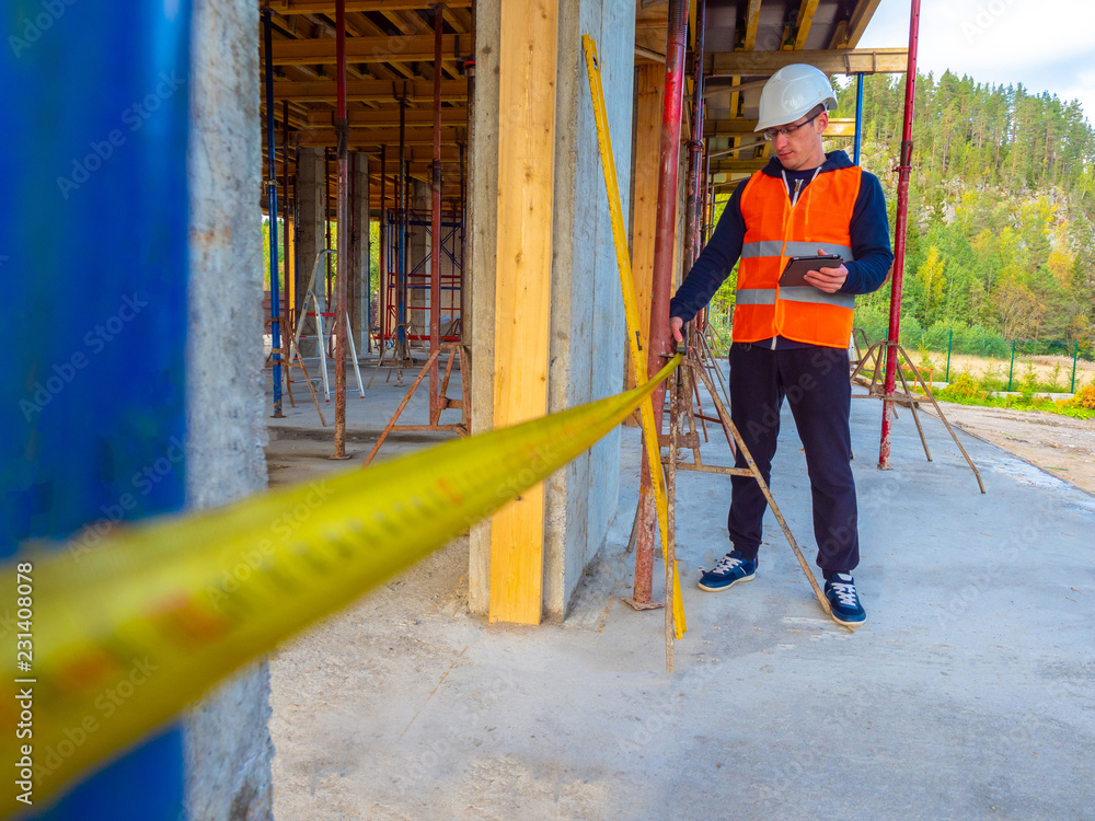 Poster the engineer checks the dimensions at the construction site. building. a man with a tape measure. me