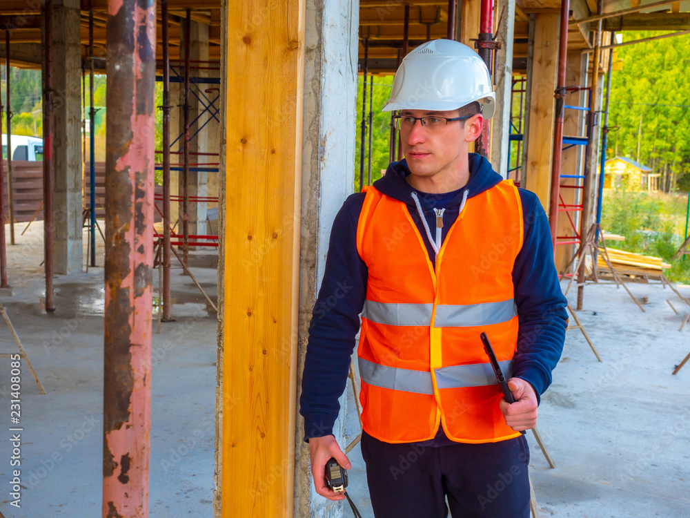 Poster the engineer checks the dimensions at the construction site. building. a man with a tape measure. me