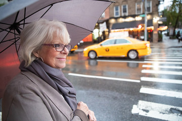 Mature senior white haired woman waiting for taxi cab in New York