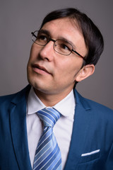 Portrait of young Asian businessman against gray background