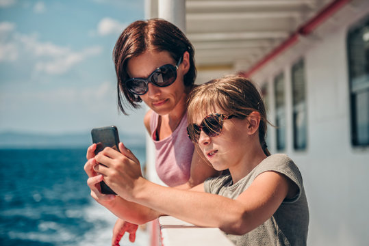Mother and daughter traveling on ferry and taking pictures