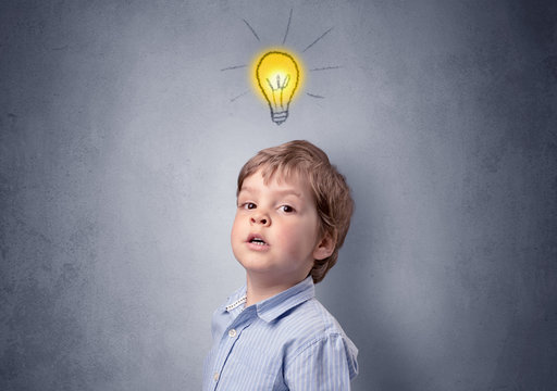 Adorable little kid mull over in front of a grey wall with idea symbol above his head