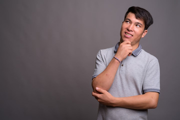 Portrait of young Asian man against gray background